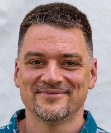 Tom Chantler, smiling, with short dark hair and a greying beard.